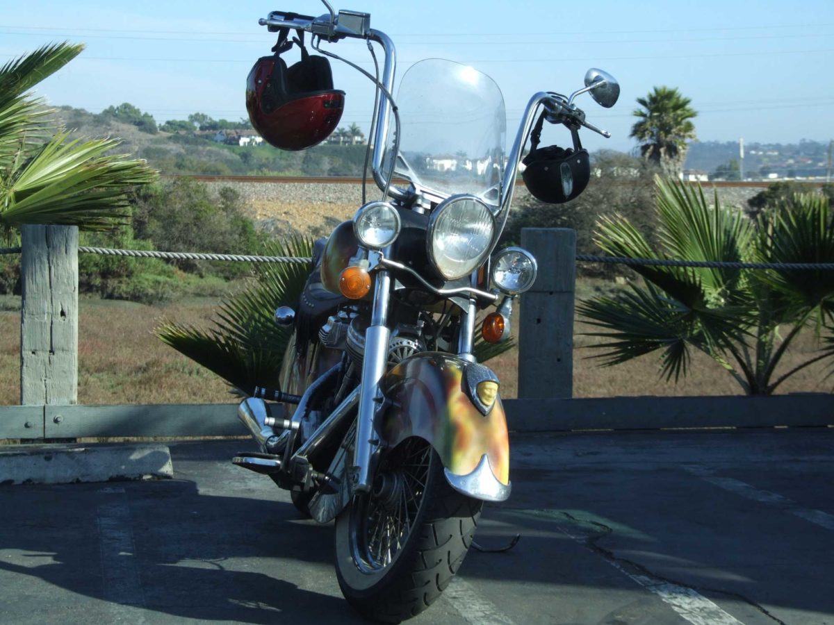 vintage custom fancy Indian Motorcycle pictured in a parking lot in Encinitas with palm trees and San Diego in background